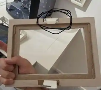 Tablet enclosure frame held up for inspection with the latch location circled